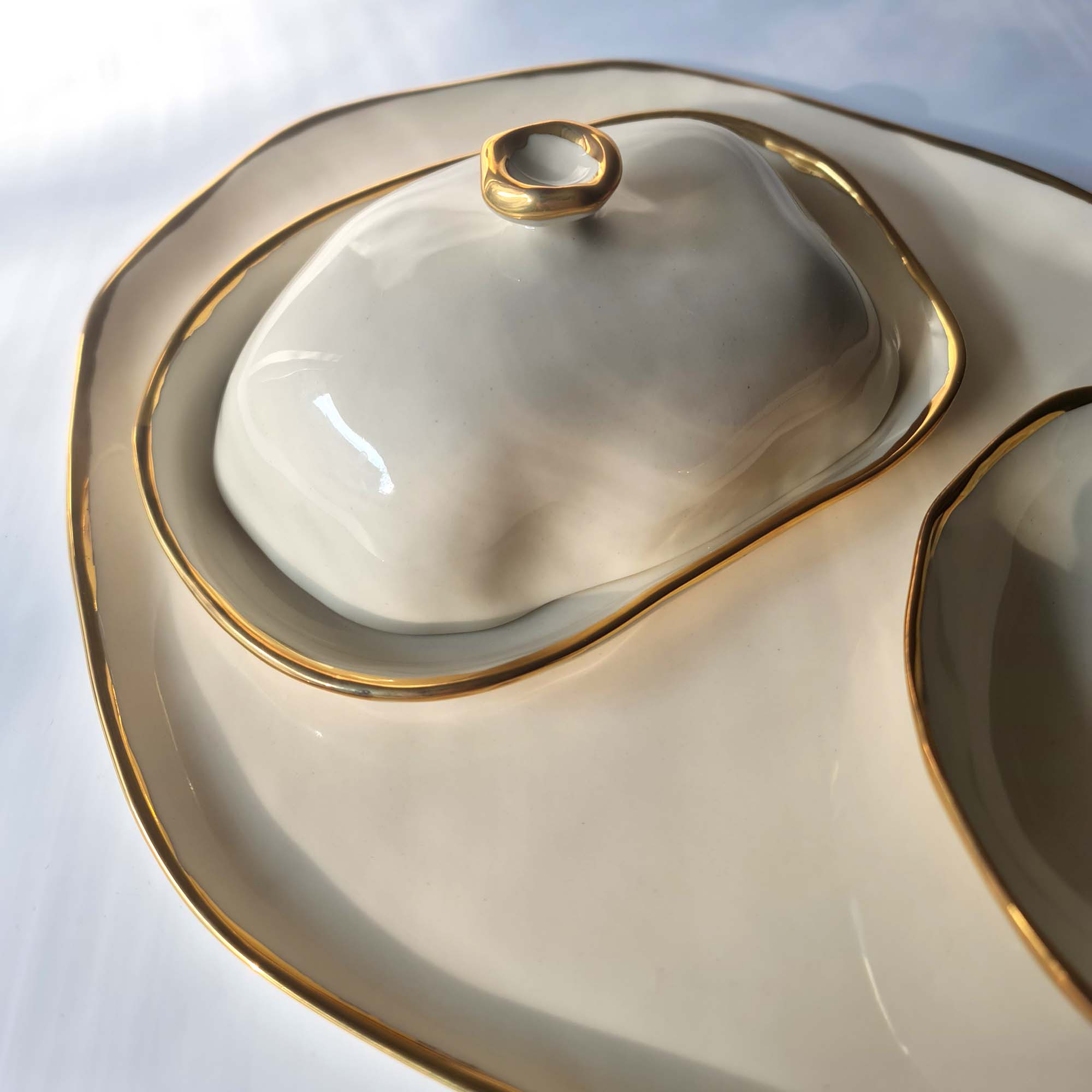 butter dish Close-up of a sculptural porcelain butter dish with organic contours and gold luster edging