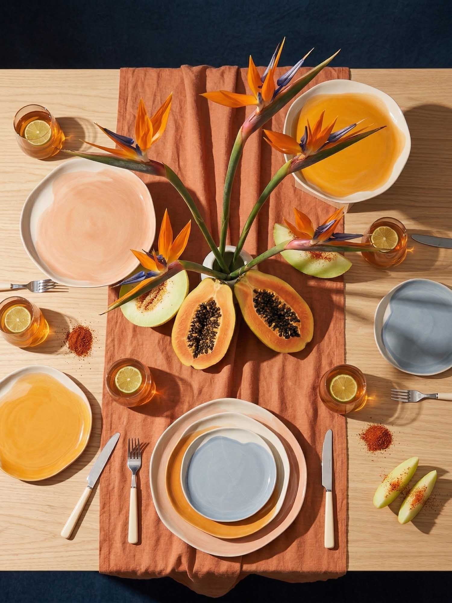 Outdoor breakfast setting with colorful porcelain tableware, food, and two people at a table.